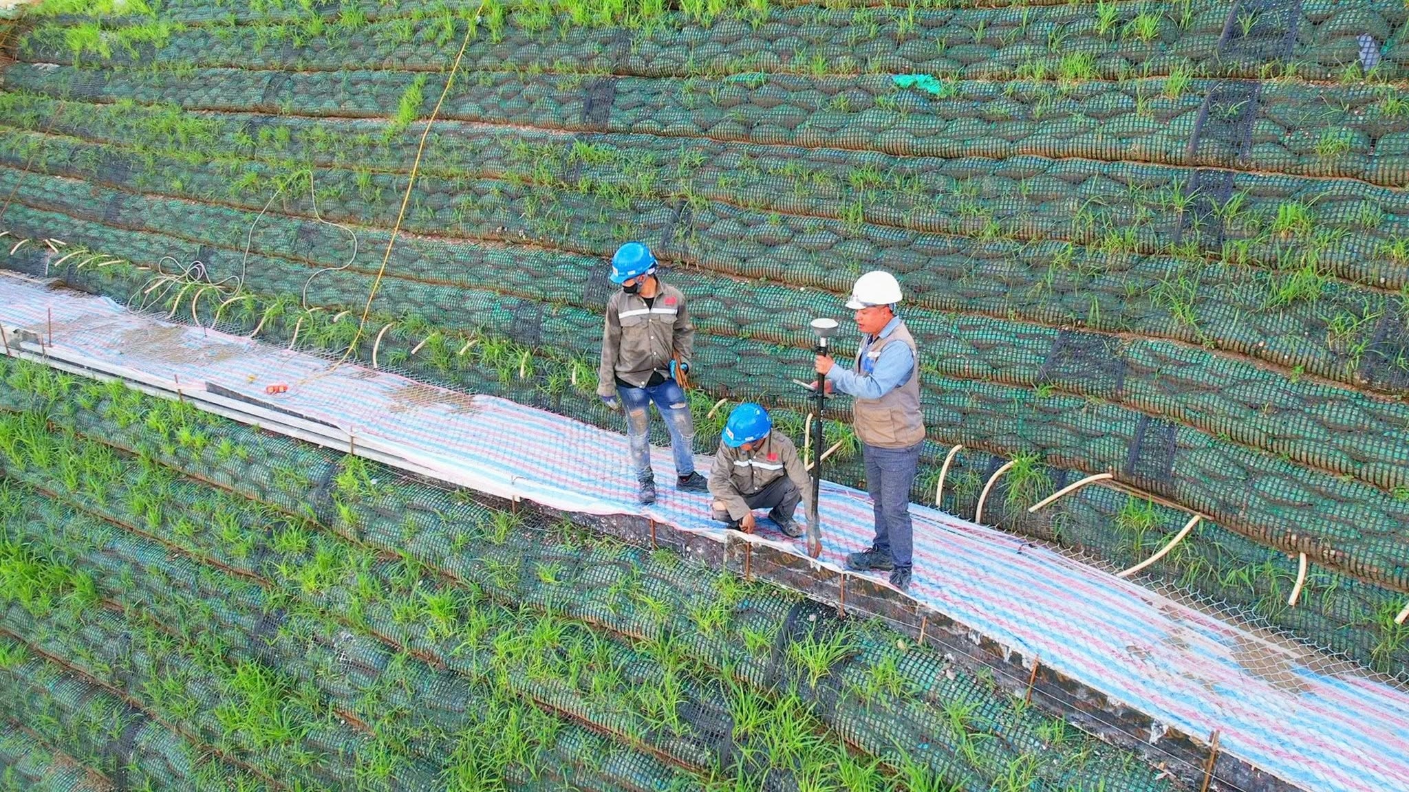 Kỹ sư Minh Đức EC tiến hành công tác trắc địa, kiểm tra chất lượng hạng mục gia cố mái dốc bằng công nghệ bao sinh thái (bao tải đất) kết hợp phủ xanh bề mặt 